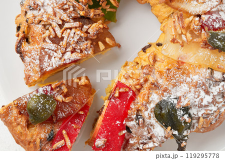A detailed view of a sliced holiday cake topped with candied cherries, almonds, and powdered sugar 119295778