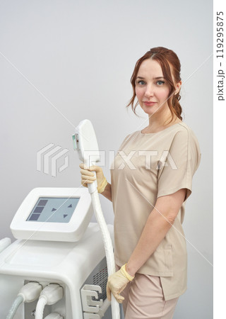 Professional aesthetician standing with advanced beauty treatment equipment Professional aesthetician standing with advanced beauty treatment equipment 119295875