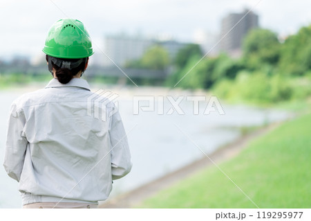 河川調査をするヘルメットをかぶった作業服姿の女性 119295977