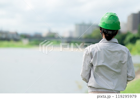 河川調査をするヘルメットをかぶった作業服姿の女性 119295979