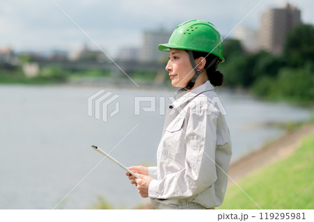 河川調査をするヘルメットをかぶった作業服姿の女性 119295981