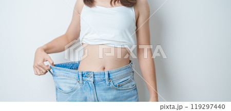 young slim female wearing big or oversize jeans, woman show healthy shape after weight loss. dieting, exercise, body fit and liposuction surgery concept 119297440