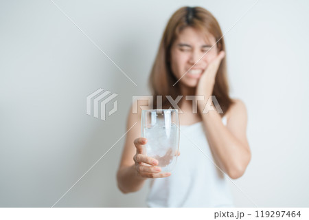 Teeth Sensitive to Cold concept. woman hold Ice Water glass and having toothache and pain after eat. Tooth Decay or Gum Disease, Grinding Teeth and Stress, Exposed Nerve Roots, Crack and Receding Gums 119297464
