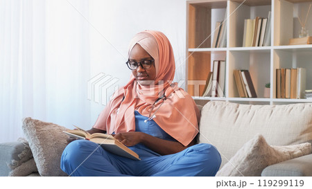 Medicine education. Disease study. Thoughtful woman intern doctor student reading professional healthcare nurse course book on couch at clinic. 119299119