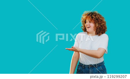 Joyful woman smiles points radiating positive energy enthusiasm isolated on blue empty space background. 119299207