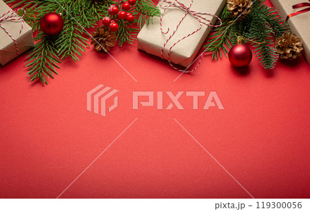 Christmas or New Year celebration red paper festive background with decoration fir tree, wrapped present boxes, cones, berries, sparkly red balls. Space for text. Christmas or New Year celebration red paper festive background with decoration fir tree, wrapped present boxes, cones, berries, sparkly red balls. Space for text. 119300056