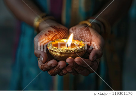 close up Woman holding lit diya lamp in hands close up Woman holding lit diya lamp in hands 119301170
