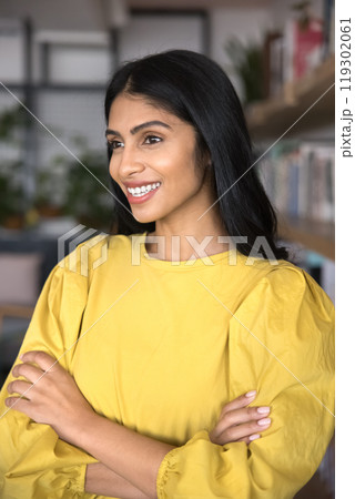 Positive beautiful young Indian student woman standing with arms crossed 119302061