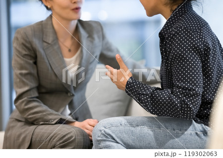 Female office employees sitting on office couch, talking, discussing tasks 119302063