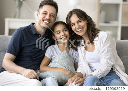Happy spouses with preteen daughter posing for portrait on sofa Happy spouses with preteen daughter posing for portrait on sofa 119302069