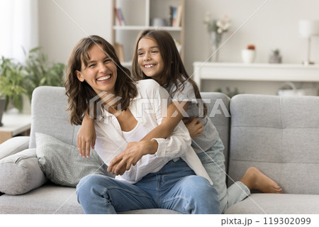 Happy laughing young mom little daughter playing tickling on couch 119302099