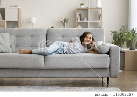 Portrait cheerful preteen girl lying on sofa in comfortable pose 119302187