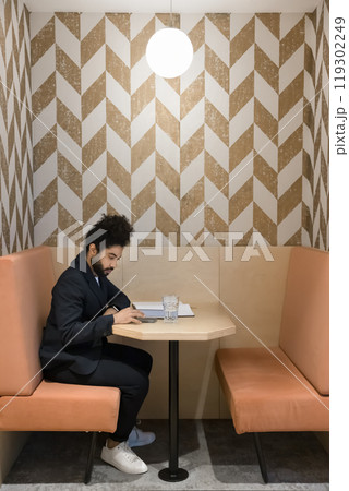 Focused young Arab employee using digital gadget in office booth Focused young Arab employee using digital gadget in office booth 119302249