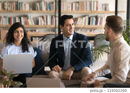 Positive confident young Latin businessman talking to colleagues in co-working 119302260