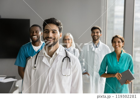 Happy young male doctor posing in front of friendly colleagues Happy young male doctor posing in front of friendly colleagues 119302281
