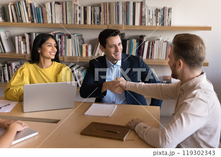 Happy young businessmen shaking hands after negotiation Happy young businessmen shaking hands after negotiation 119302343