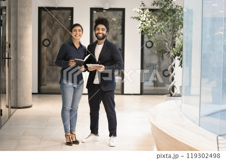 Two multiethnic happy successful business partners standing in office hall 119302498