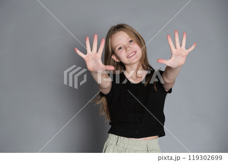 Girl with hands stretched out, beaming with cheer. Reflects the uninhibited joy and spirited expression of childhood. Girl with hands stretched out, beaming with cheer. Reflects the uninhibited joy and spirited expression of childhood. 119302699