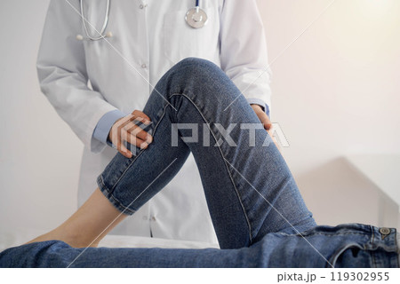Doctor and patient are at the medical inspection in clinic. Orthopedic examines the knee of a young woman. Medicine concept Doctor and patient are at the medical inspection in clinic. Orthopedic examines the knee of a young woman. Medicine concept 119302955