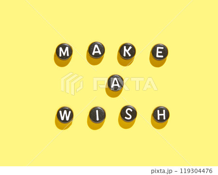 Motivational message make a wish with black letter beads on bright yellow 119304476