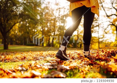 Close-up of feet in hiking boots in clearing among fallen leaves in sunny autumn park. outdoor walk. Close-up of feet in hiking boots in clearing among fallen leaves in sunny autumn park. outdoor walk. 119304930