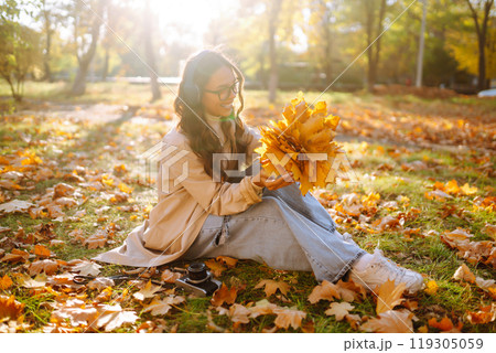 Young woman taking pictures in the autumn forest. Lady Walking In Fall Park With Yellow Foliage. 119305059