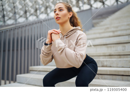 Sports woman in sportswear does exercises outdoors. . Sport, active lifestyle, healthy lifestyle concept. 119305400