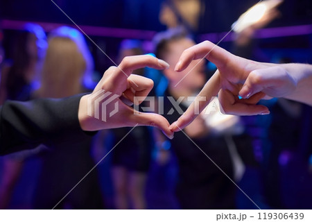 Hands Forming a Heart Shape in the Midst of a Vibrant and Joyful Celebration Event Hands Forming a Heart Shape in the Midst of a Vibrant and Joyful Celebration Event 119306439