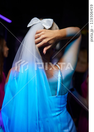 An Elegant Bride in a beautiful Veil and Bow, enjoying a vibrant Nightclub with friends An Elegant Bride in a beautiful Veil and Bow, enjoying a vibrant Nightclub with friends 119306459
