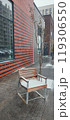 A wooden chair covered in snow beside a modern building on a chilly winter day in an urban neighborhood 119306550