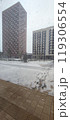Snowfall blankets urban landscape outside residential buildings during winter morning 119306554