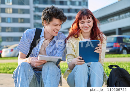 Teenage college students guy and girl talking, sitting outdoor Teenage college students guy and girl talking, sitting outdoor 119306723