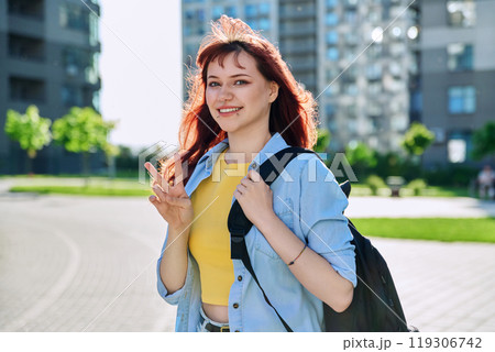 Young smiling red-haired hipster female with facial piercing looking at camera outdoor Young smiling red-haired hipster female with facial piercing looking at camera outdoor 119306742