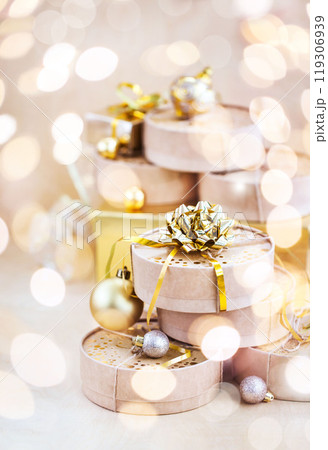 Christmas or New year round kraft gift boxes, gold holiday balls on a bokeh background of twinkling party lights of garland Christmas or New year round kraft gift boxes, gold holiday balls on a bokeh background of twinkling party lights of garland 119306939