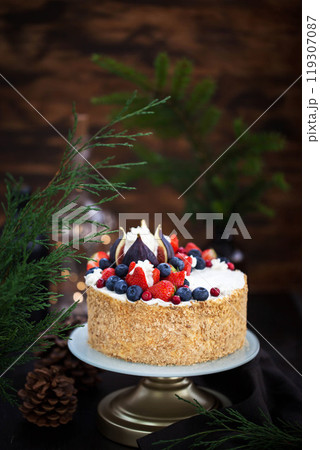 Homemade Honey cake, layered and custard cream cake decorated with fresh figs, strawberries and blueberries 119307087