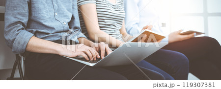 Group of casual dressed business people working at meeting or conference in sunny office, close-up of hands. Businessman using tablet computer 119307381