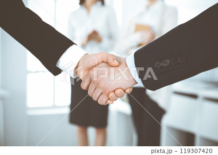 Businessman and woman shaking hands in office. Concept of handshake as success symbol in business Businessman and woman shaking hands in office. Concept of handshake as success symbol in business 119307420