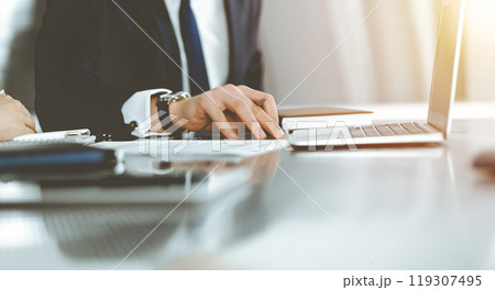 Unknown businessmen and woman sitting, working and discussing questions at meeting in sunny office, close-up. Success concept 119307495