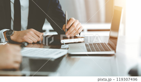 Unknown businessmen and woman sitting, working and discussing questions at meeting in sunny office, close-up. Success concept 119307496