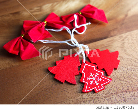 New Year and Christmas toys: red bows and wooden Christmas trees on a wooden board background. Holiday decor, religion and culture New Year and Christmas toys: red bows and wooden Christmas trees on a wooden board background. Holiday decor, religion and culture 119307538