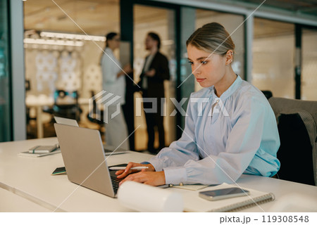 A Focused Young Professional Engaged in Significant Tasks at a Contemporary Office Desk Space A Focused Young Professional Engaged in Significant Tasks at a Contemporary Office Desk Space 119308548
