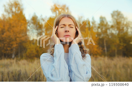 Upset exhausted young woman with headache, pain tension in the head, suffers from migraine outdoors 119308640