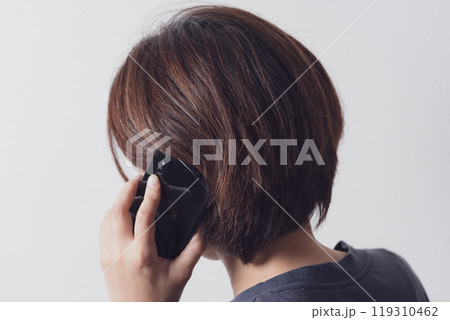 スマホで通話をする中年女性の後ろ姿 119310462
