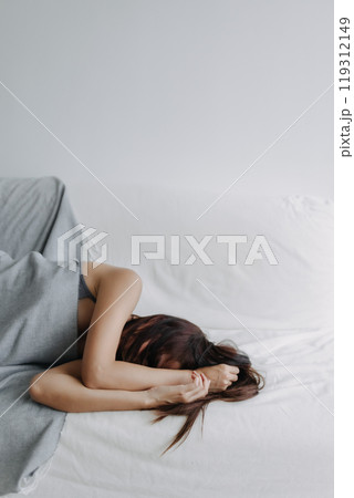 Woman does not want to wake up, using her arms to block the light. Woman does not want to wake up, using her arms to block the light. 119312149