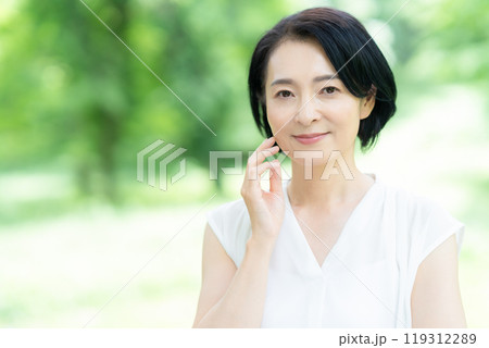 新緑の中でスキンケアをするミドルの女性 119312289