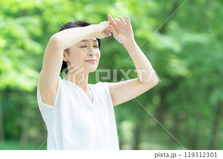 新緑の中でスキンケアをするミドルの女性 119312301