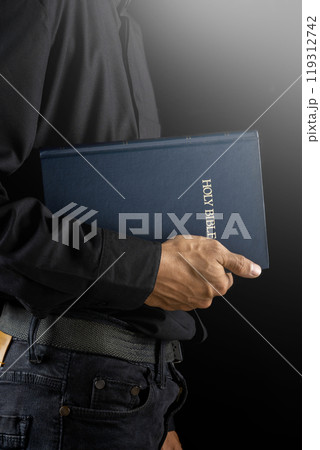 Man holding a holy bible in his hand. Symbol of faith and worship in God. People christianity prayer in church 119312742