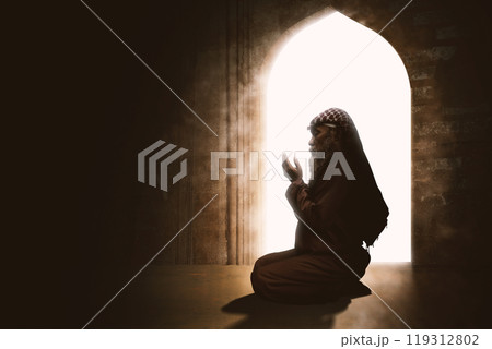 Religious old Muslim man kneeling and praying while raised hands in the mosque 119312802