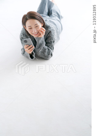 床に寝転びスマホを操作する女性 床に寝転びスマホを操作する女性 119312895