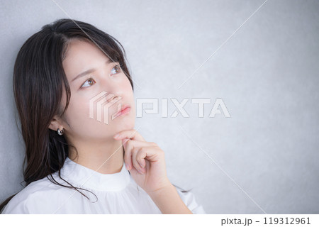上を向いて考える若い女性のクローズアップ　グレーバック 119312961